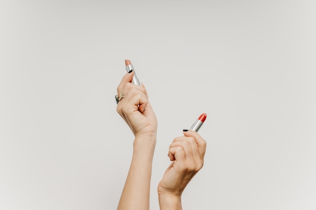 Photo low section of woman holding hands against white background with lipsticks