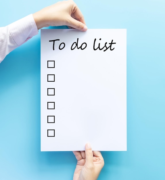 Low section of woman holding paper against blue background