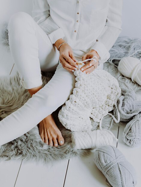 Low section of woman knitting scarf at home