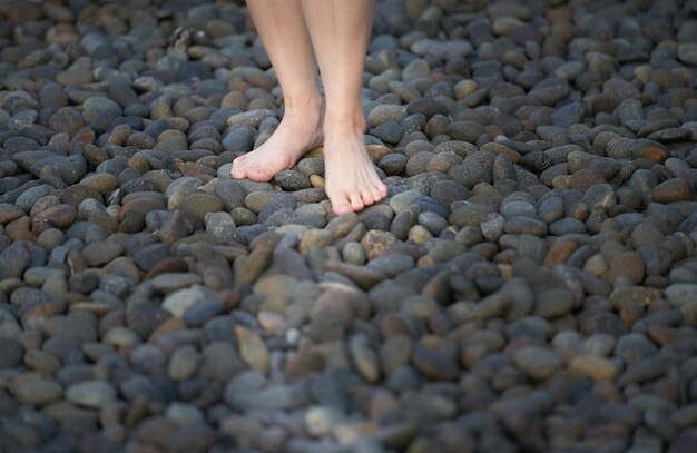 Foto sezione bassa delle gambe di una donna su ciottoli sulla spiaggia