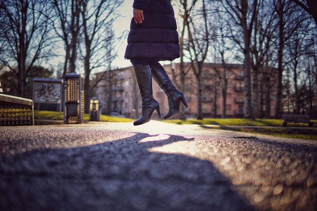 Photo low section of woman levitating against bare trees