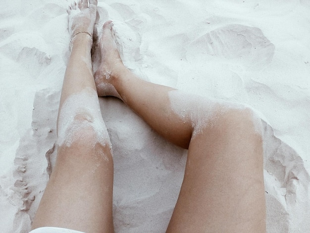 Foto sezione bassa di una donna sdraiata sulla sabbia sulla spiaggia