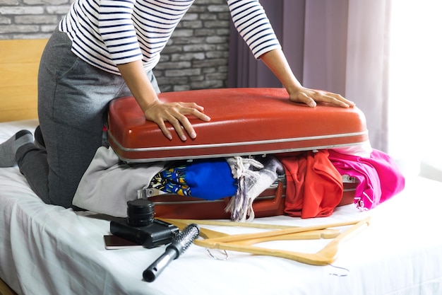 Foto sezione inferiore di una donna che impaccha una valigia sul letto a casa