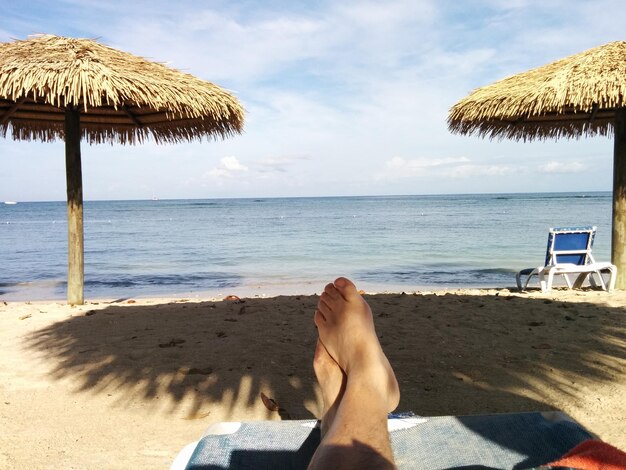 Photo low section of woman relaxing at beach against sky