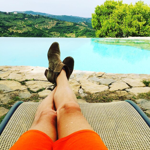 Photo low section of woman relaxing by infinity pool