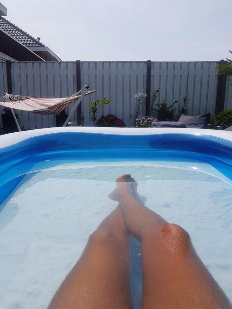 Low section of woman relaxing in swimming pool