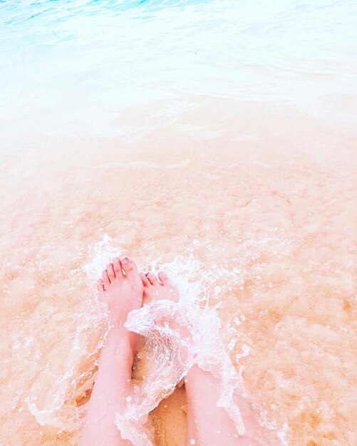 Foto sezione inferiore di una donna che si riposa sulla riva sulla spiaggia