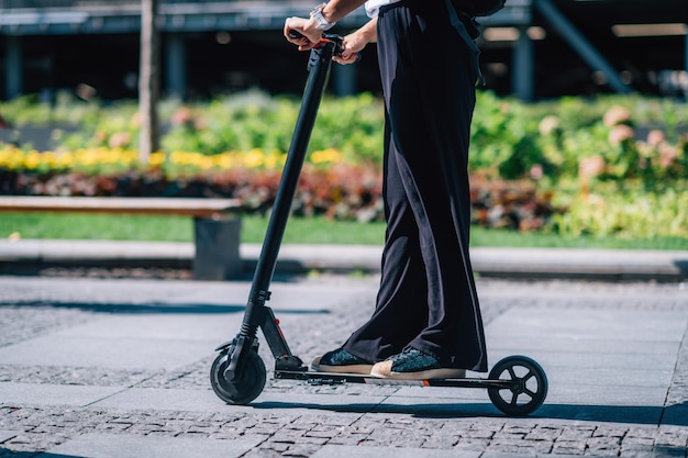 Foto sezione bassa di una donna che guida uno scooter elettrico sul sentiero