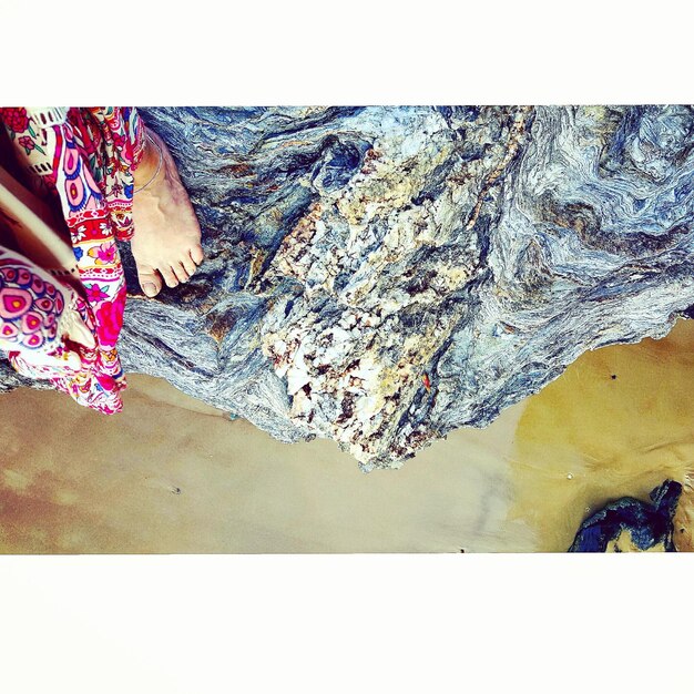 Foto sezione bassa di una donna sulla roccia sulla spiaggia