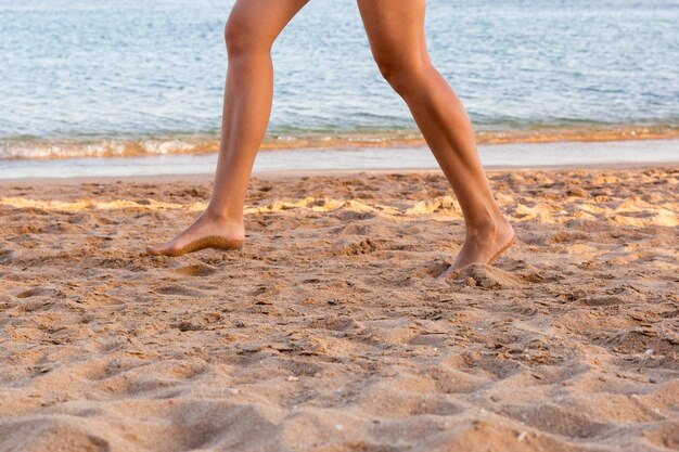 Foto sezione bassa di una donna che corre sulla spiaggia