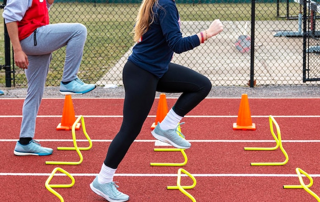 Foto sezione bassa di una donna che corre su ostacoli in una pista sportiva