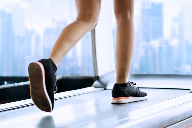 Low section of woman running on treadmill at gym