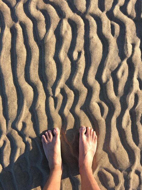 Foto sezione bassa di una donna sulla sabbia sulla spiaggia