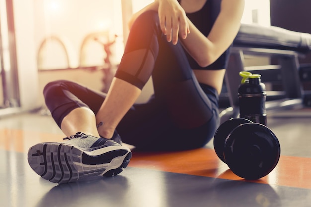 Foto sezione bassa di una donna seduta da manubri in palestra