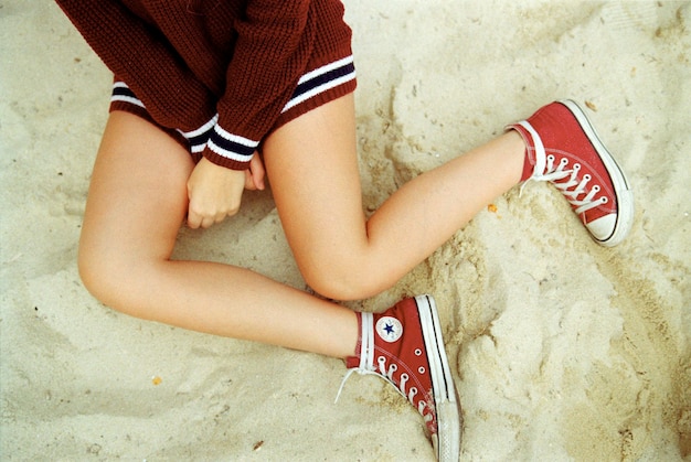 low section of woman sitting on sand
