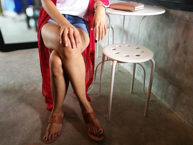 Low section of woman sitting on stool in cafe