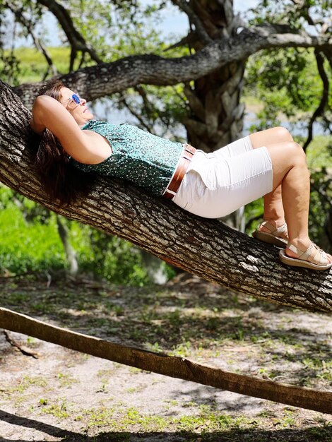 Foto sezione bassa di una donna seduta sul tronco di un albero