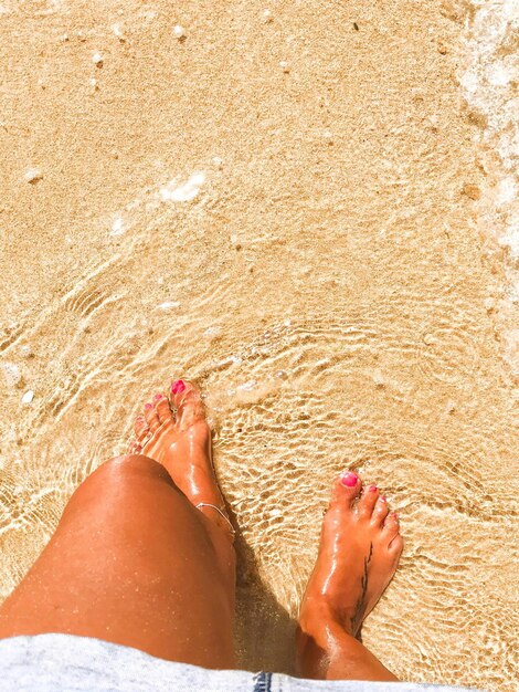 Foto sezione bassa di una donna in piedi sulla spiaggia