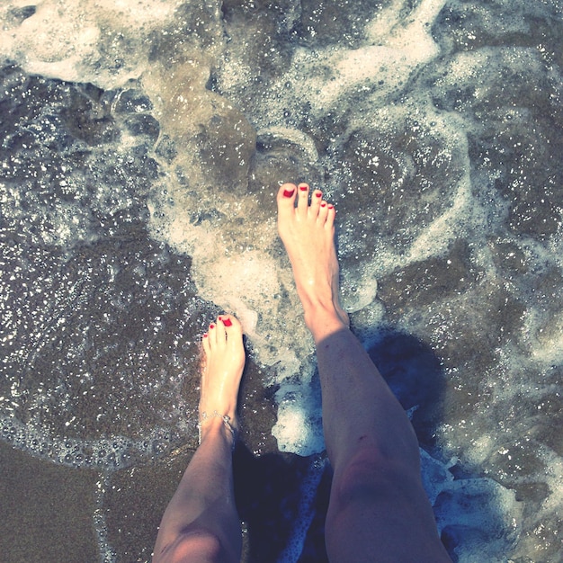 Foto sezione bassa di una donna in piedi sulla spiaggia