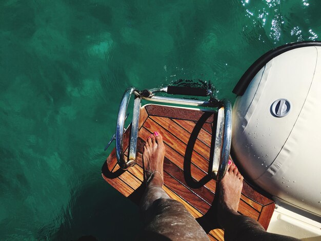 Foto sezione bassa di una donna in piedi su una barca in mare