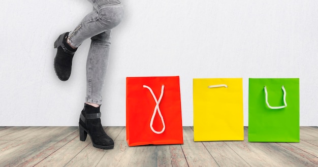 low section of woman standing by shopping bags against yellow wall