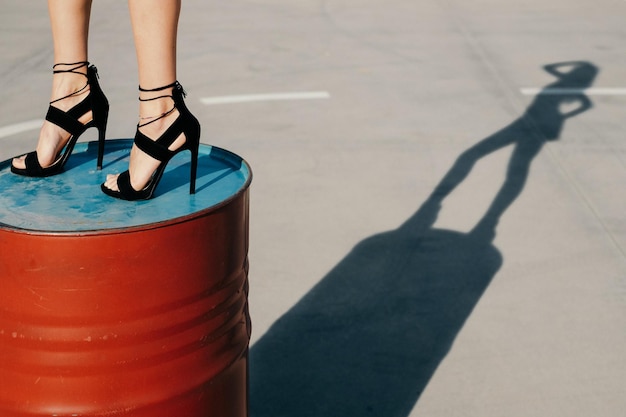 Photo low section of woman standing on red drum at footpath