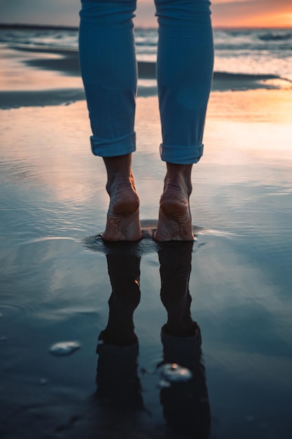 Foto sezione bassa di una donna in piedi sulla riva del mare contro il cielo durante il tramonto