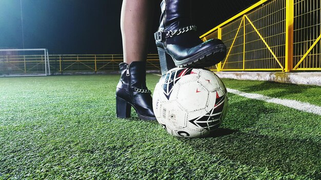 Low section of woman standing with soccer on field