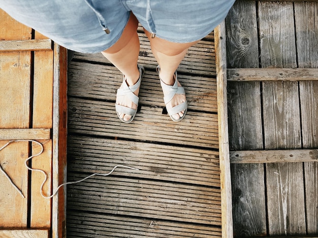 Foto sezione bassa di una donna in piedi su un marciapiede di legno
