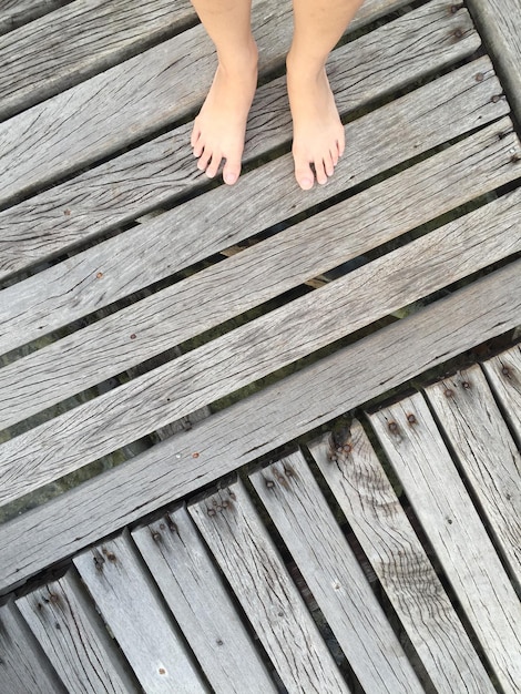 Foto sezione bassa di una donna in piedi su un molo di legno