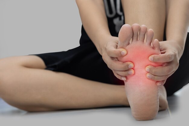 Low section of woman suffering from barefoot pain against white background