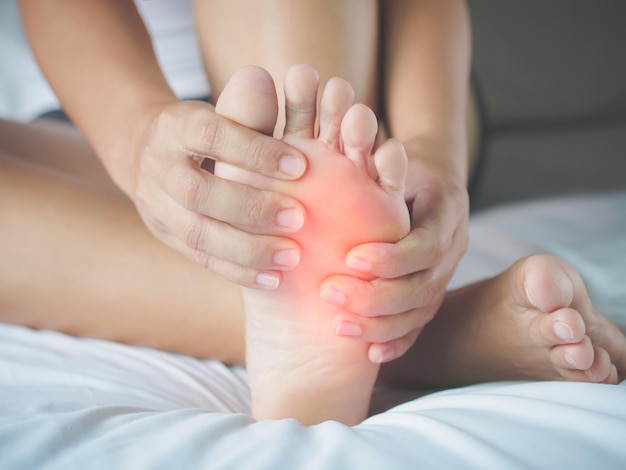 Low section of woman suffering from barefoot pain at home