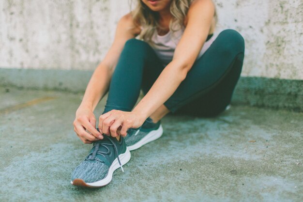 low section of woman tying shoelace on footpath