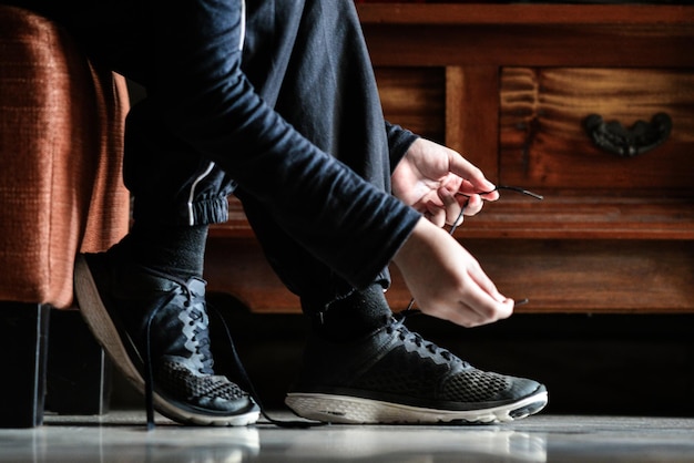 Photo low section of woman tying shoelace at home