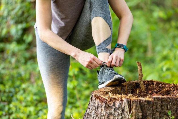 Photo low section of woman tying shoelace on tree stump