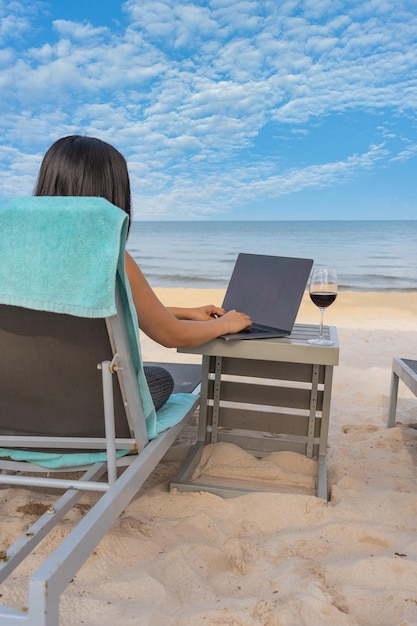 low section of woman using laptop at beach