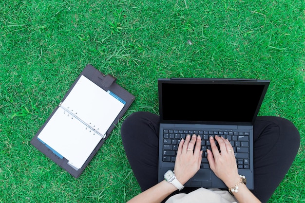 low section of woman using laptop on field