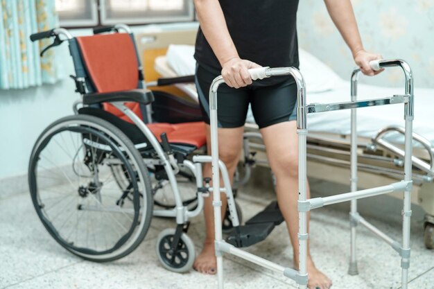 Low section of woman walking with help of walker on floor