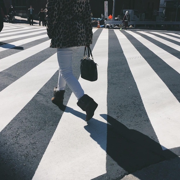 Photo low section of woman walking on zebra crossing