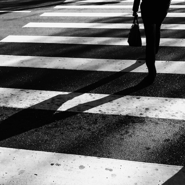 Low section of woman walking on zebra crossing