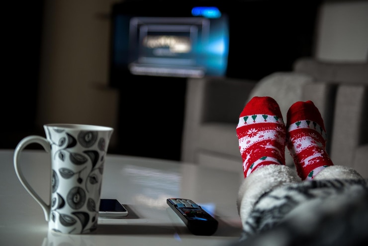 Photo low section of woman in warm clothing sitting by cup and technology on table at home