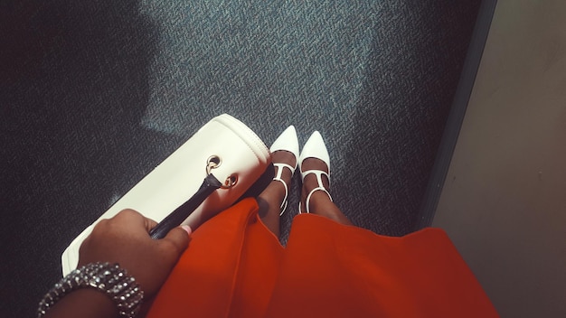 Foto sezione bassa di donna che indossa scarpe in piedi nel corridoio