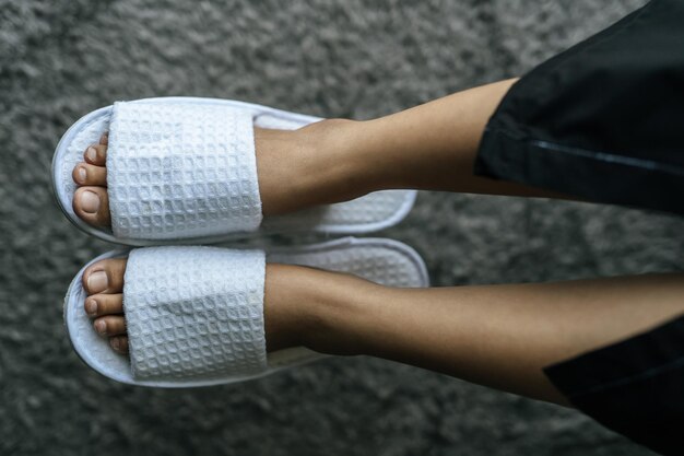 Low section of woman wearing white flip-flops