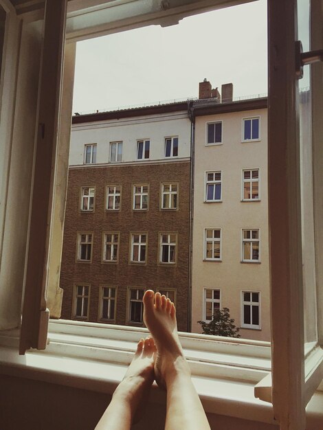 Foto sezione bassa della donna sulla finestra dell'edificio.