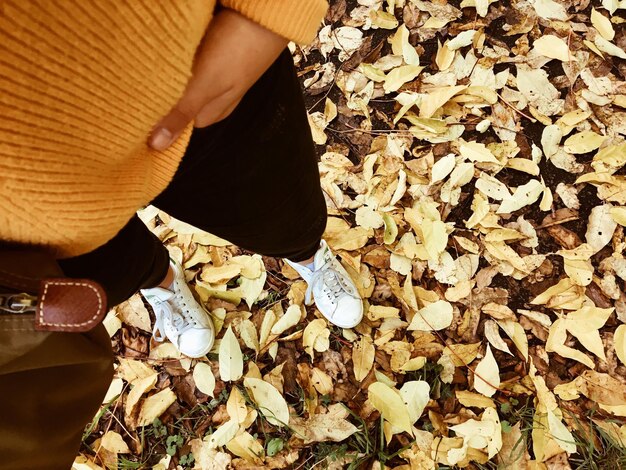 Photo low section of woman with fallen leaves