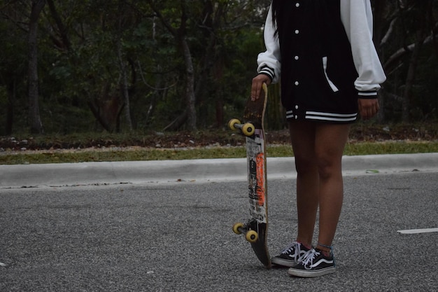 Photo low section of woman with skateboard standing on road