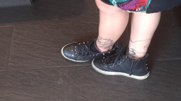 Photo low section of woman with tattoo standing on tiled floor