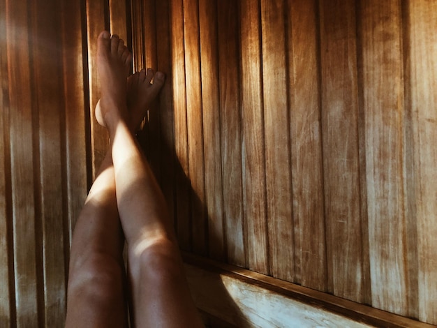 Foto sezione bassa di una donna in una sauna a secco in legno