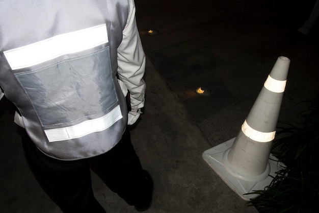 Foto sezione bassa di un lavoratore in piedi vicino al cono stradale di notte