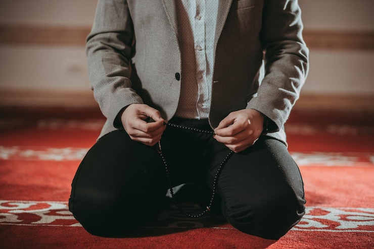 Photo low section of young man praying while sitting at home